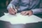The image shows a person signing a contract.